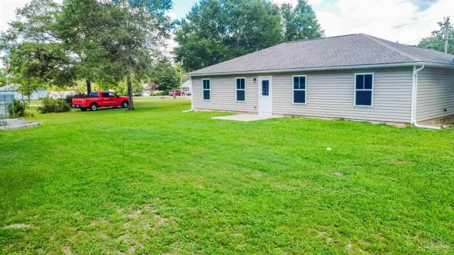 a view of a house with a yard and large trees