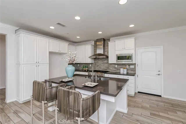 a kitchen with stainless steel appliances granite countertop a stove a sink dishwasher a refrigerator and white cabinets with wooden floor