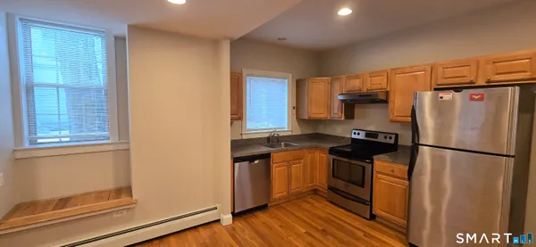 a kitchen with stainless steel appliances granite countertop a refrigerator a stove a sink and a window