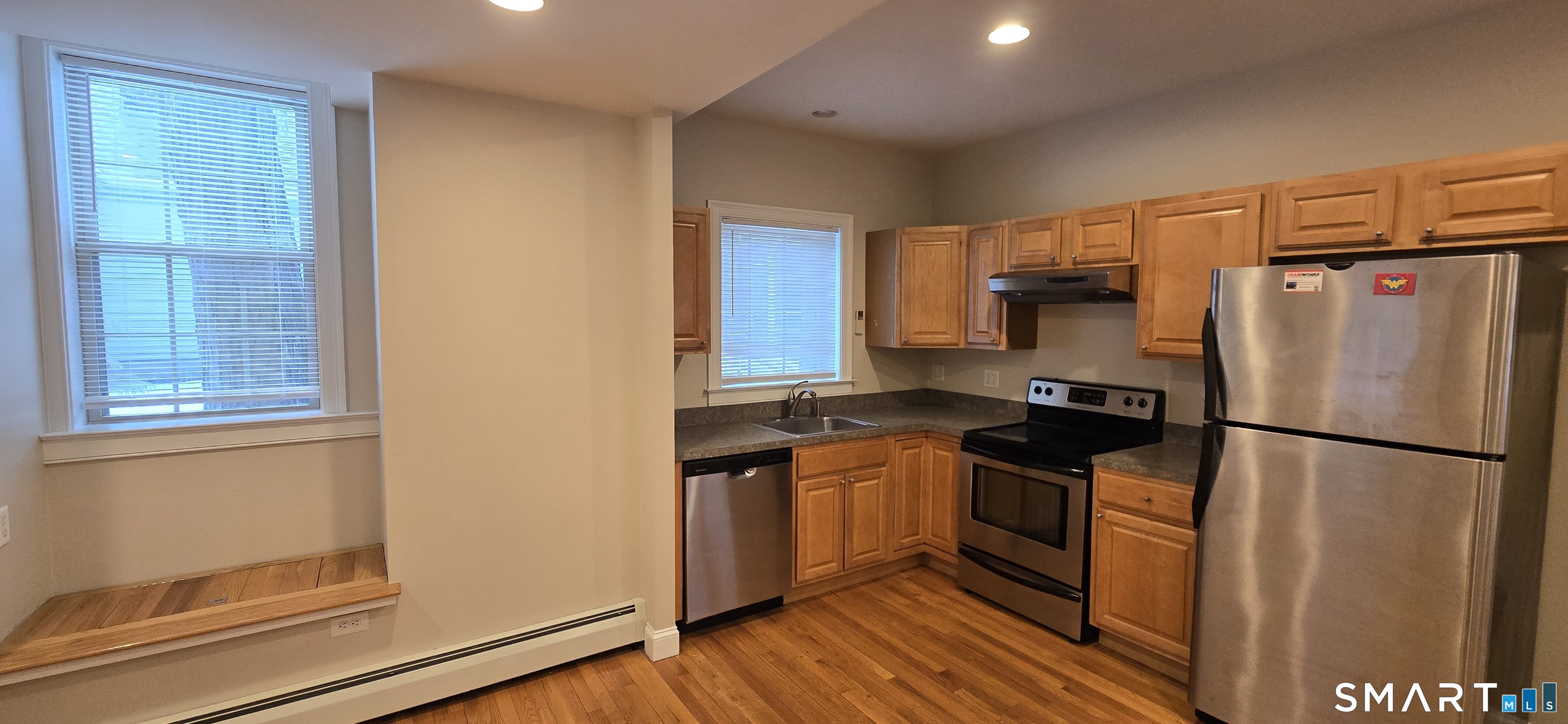 a kitchen with stainless steel appliances granite countertop a refrigerator a stove a sink and a window