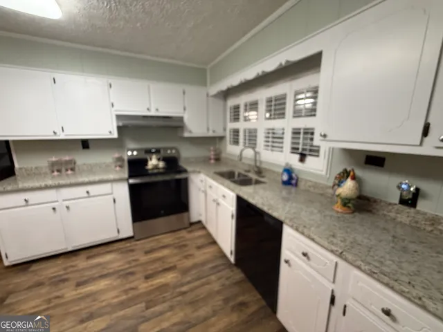 a kitchen with granite countertop a sink a stove and cabinets