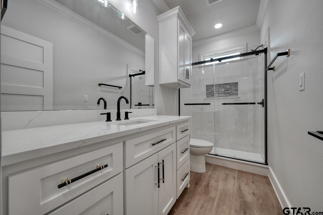 19383 Ridge Point Circle Lindale, TX 75771 - Photo 36 of 48 a bathroom with a double vanity sink a toilet and a shower