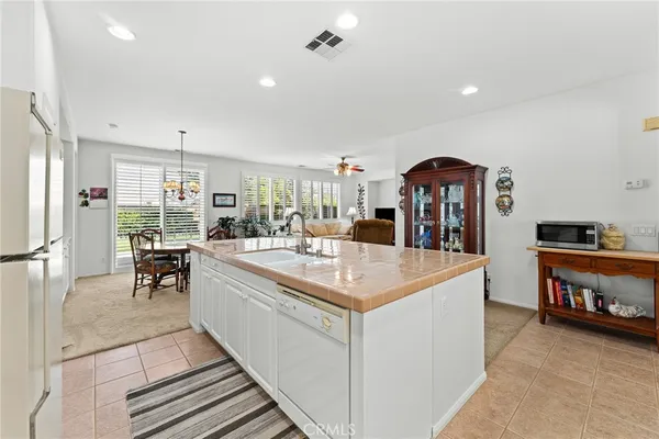 a large white kitchen with sink a refrigerator and chairs
