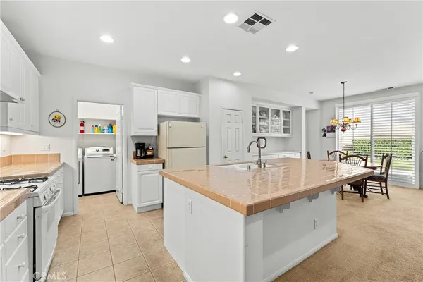 a large white kitchen with a stove a refrigerator a oven a dining table and chairs