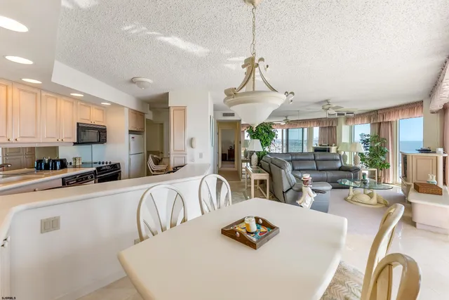 a view of a dining room and livingroom with furniture wooden floor a chandelier