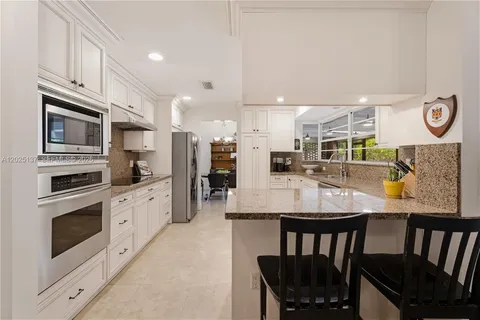 a large kitchen with stainless steel appliances kitchen island granite countertop a table chairs and a refrigerator