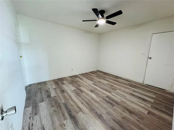 an empty room with ceiling fan and window