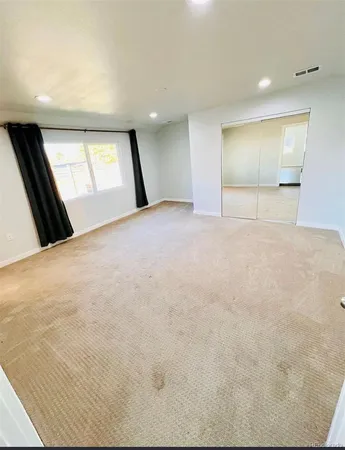 a view of an empty room with window and wooden floor