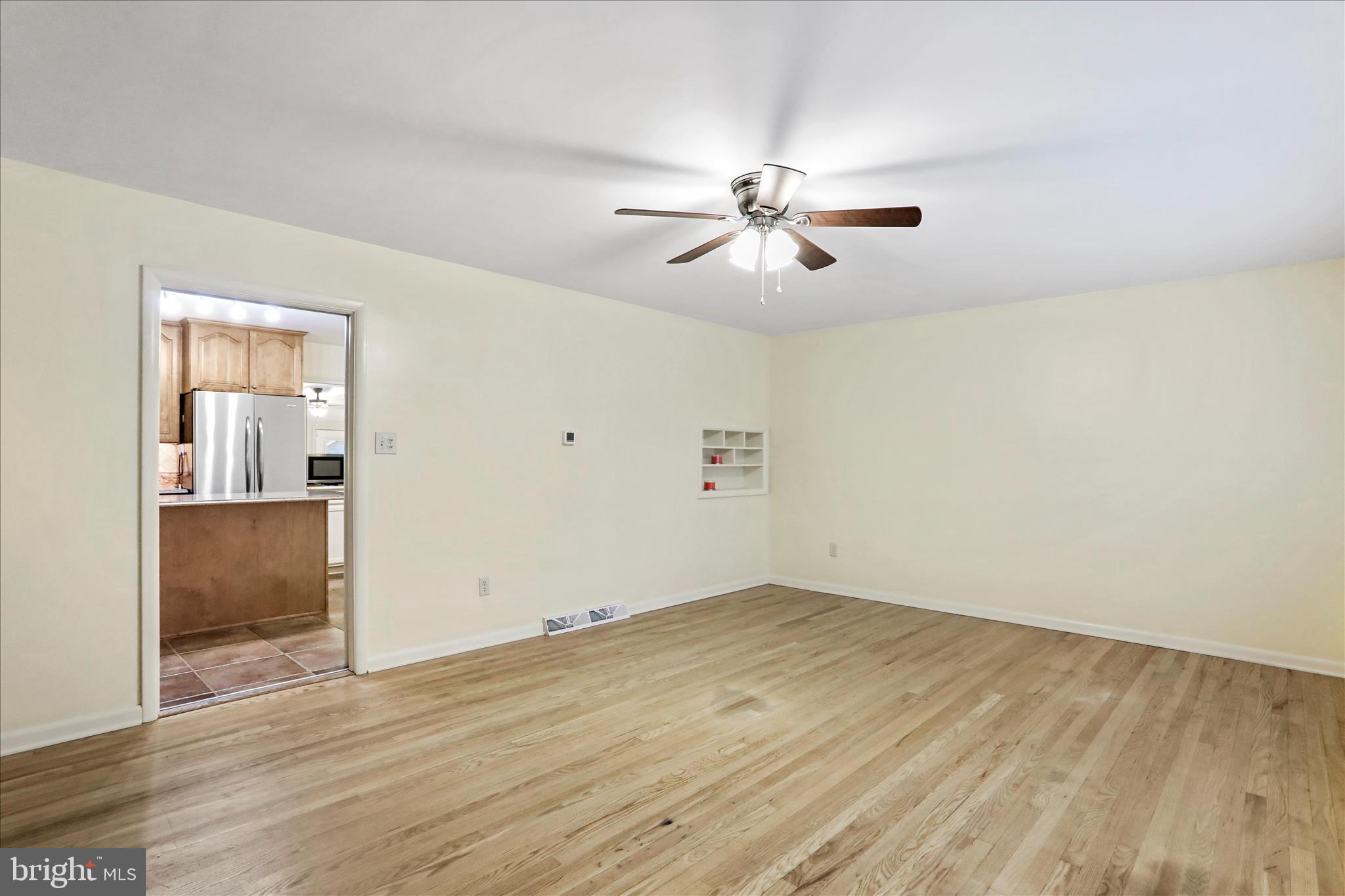 19734 Longmeadow Road Hagerstown, MD 21742 - Photo 5 of 45 an empty room with wooden floor chandelier fan and windows