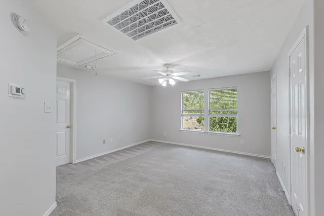 an empty room with a window and a fan