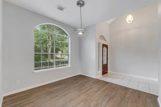 an empty room with wooden floor exposed radiator and windows