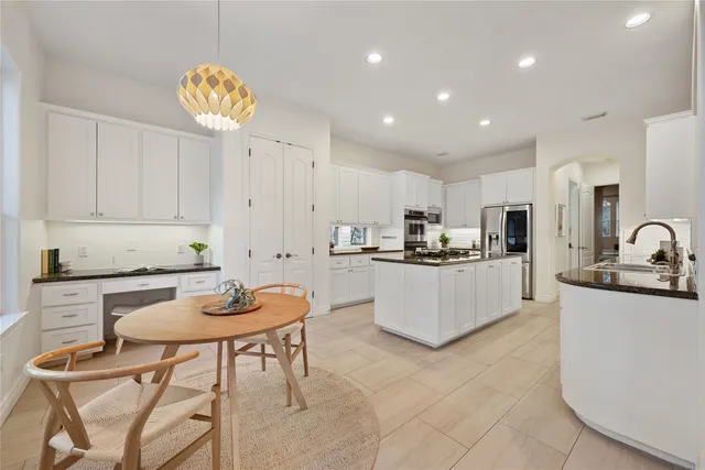 a kitchen with stainless steel appliances granite countertop a stove top oven a sink a refrigerator and white cabinets