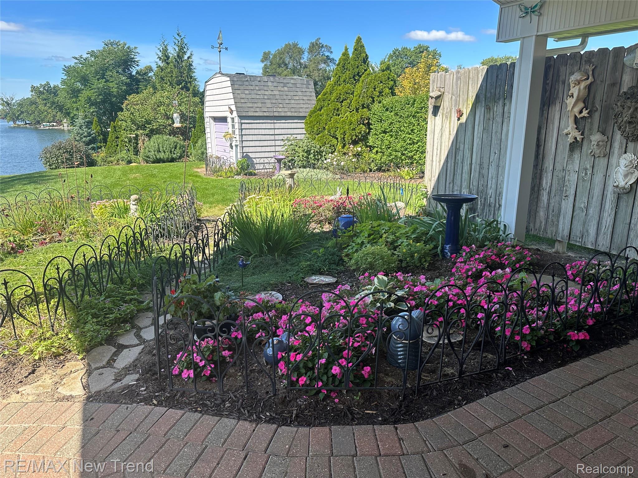 2529 South Commerce Road Walled Lake, MI 48390 - Photo 52 of 66 Waterfront property featuring a manicured lawn, an ornamental garden with flowering plants, and a garden shed with a gable roof