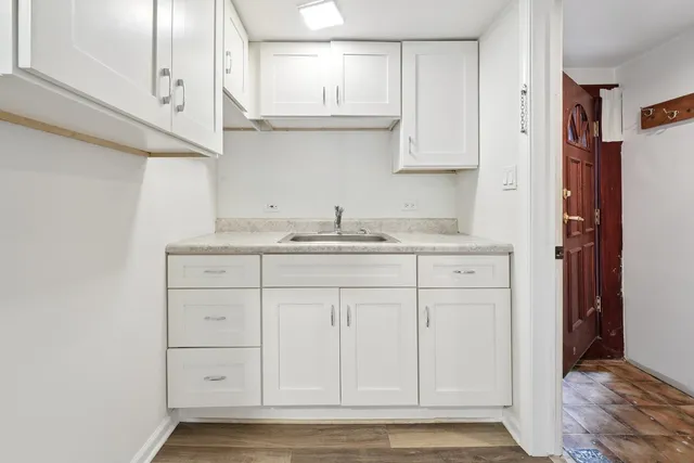 a kitchen with white cabinets and sink
