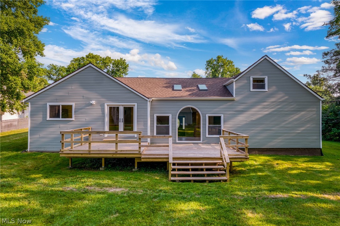 Back of house with a deck and a lawn
