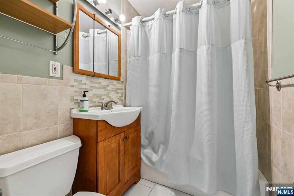 18 Scher Place Passaic, NJ 07055 - Photo 14 of 22 a bathroom with a sink a toilet and shower curtain