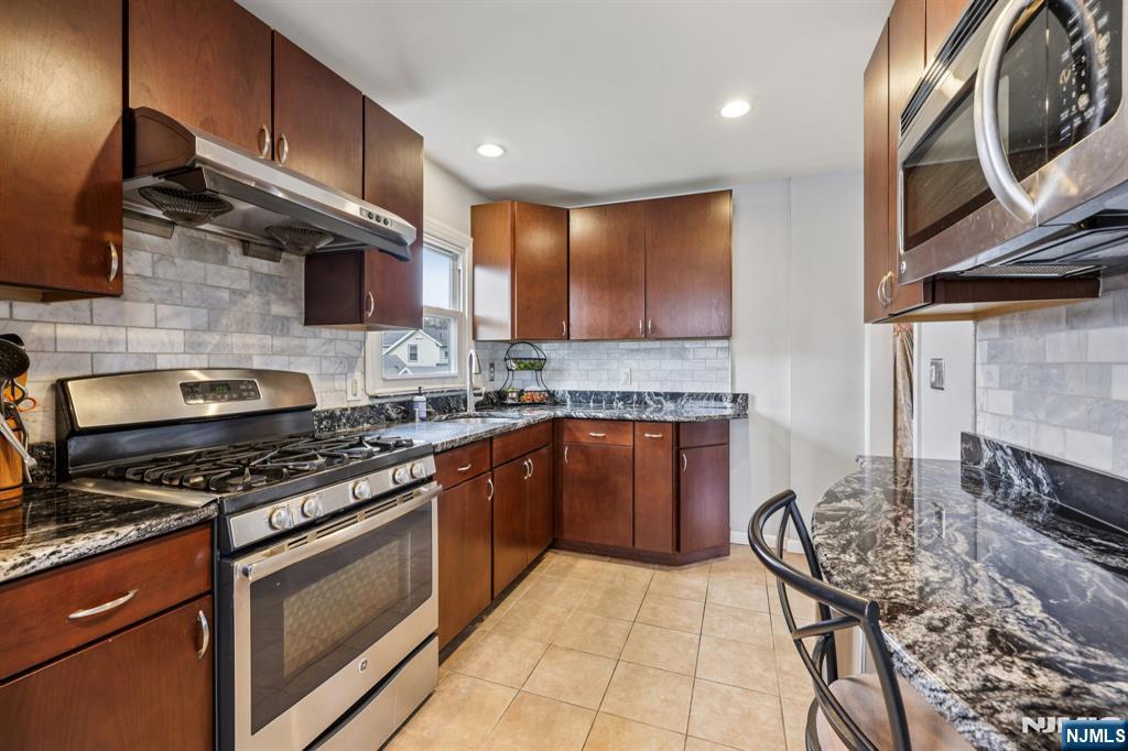 18 Scher Place Passaic, NJ 07055 - Photo 8 of 22 a kitchen with stainless steel appliances granite countertop a stove a sink and a microwave
