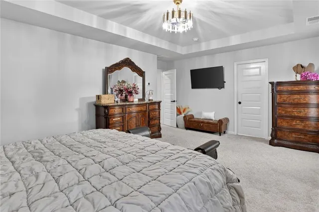 a spacious bedroom with a large bed and a chandelier