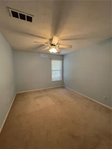 en empty room with windows and ceiling fan