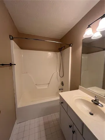 a bathroom with a granite countertop shower sink and mirror