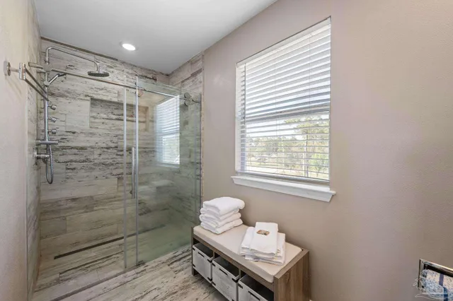 a bathroom with a shower a sink and a window