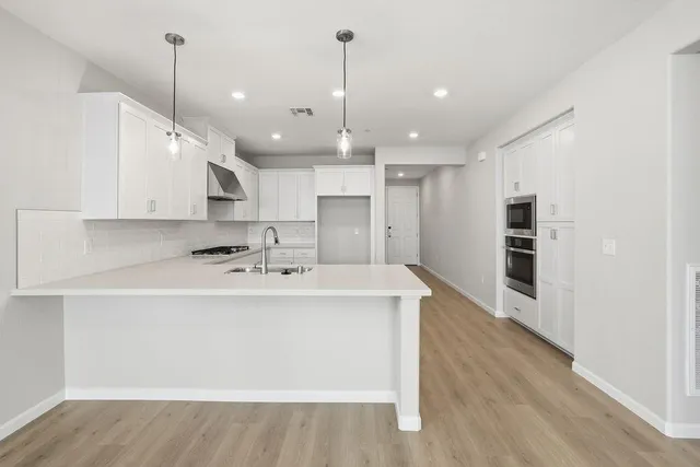a view of a kitchen with kitchen island a sink stainless steel appliances and a counter top