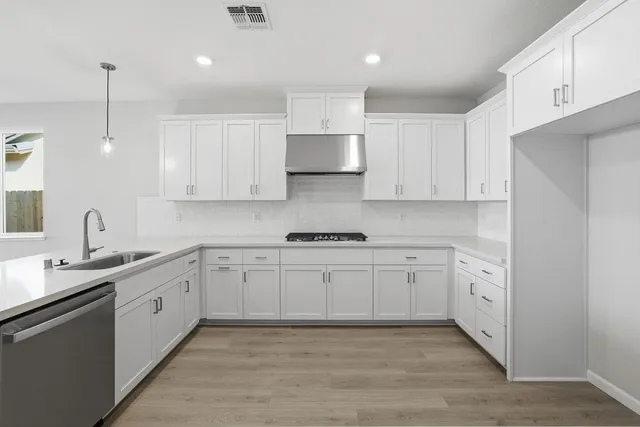 a kitchen with white cabinets appliances and sink