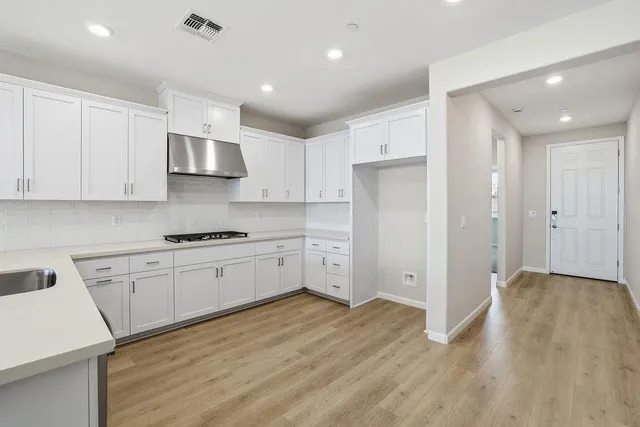 a large kitchen with stainless steel appliances granite countertop a large stove a sink dishwasher and a refrigerator with wooden floor