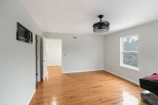 a view of an empty room with wooden floor and a window