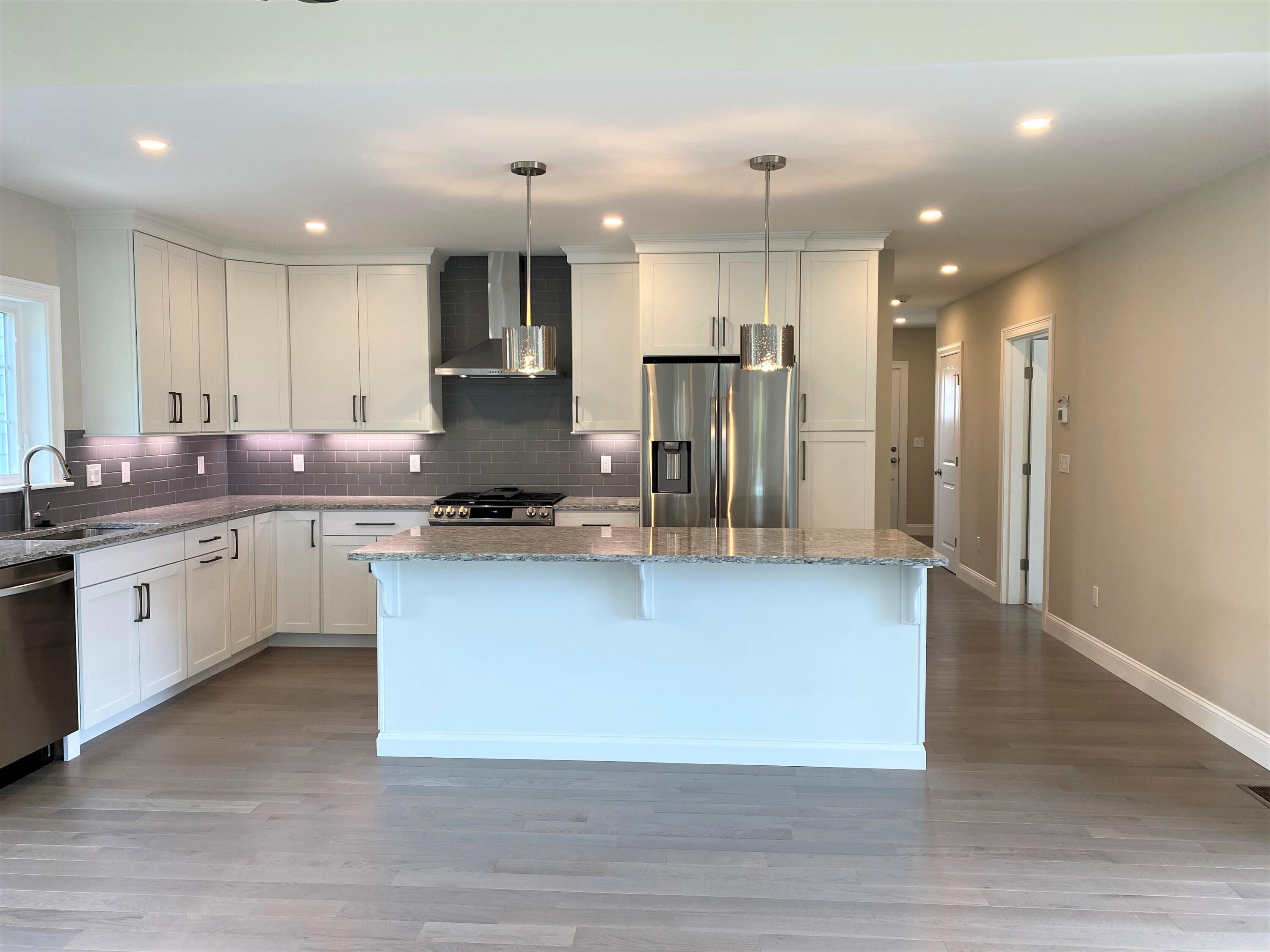 18 Cobblestone Circle Mashpee, MA 02649 - Photo 3 of 41 a large kitchen with stainless steel appliances kitchen island granite countertop a stove a sink a refrigerator and white cabinets with wooden floor