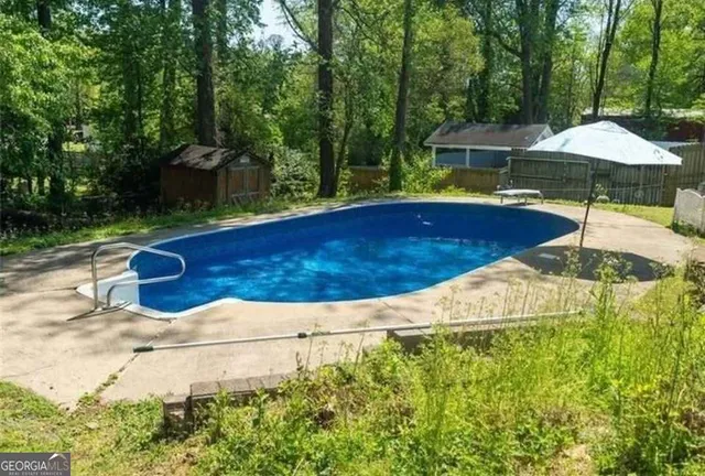 a view of pool with lawn chairs under an umbrella