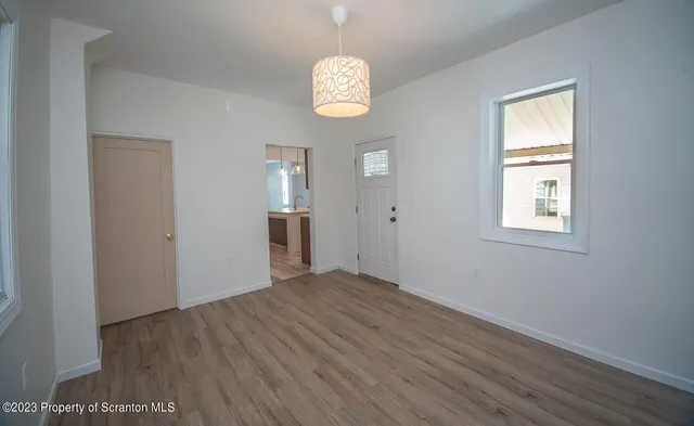 a view of an empty room with window and wooden floor