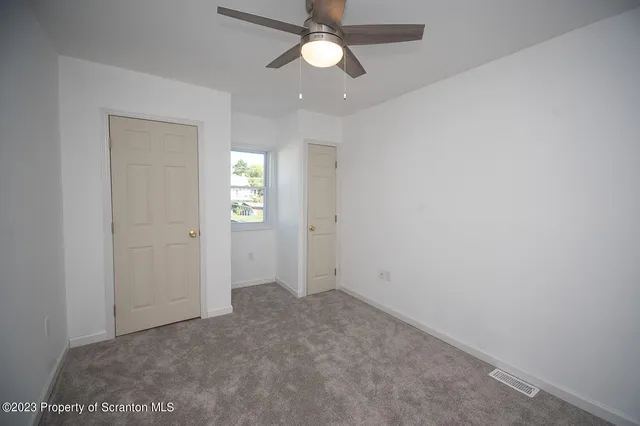 an empty room with closet and a chandelier fan