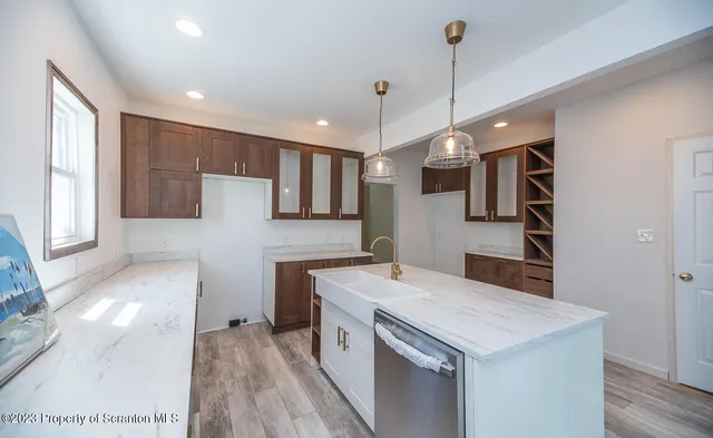 a kitchen that has a sink a microwave oven a stove and white cabinets with wooden floor
