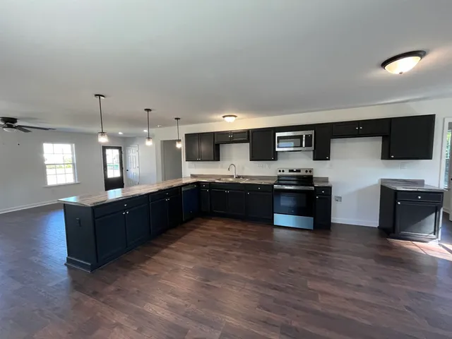a large kitchen with a large counter top cabinets appliances and a window
