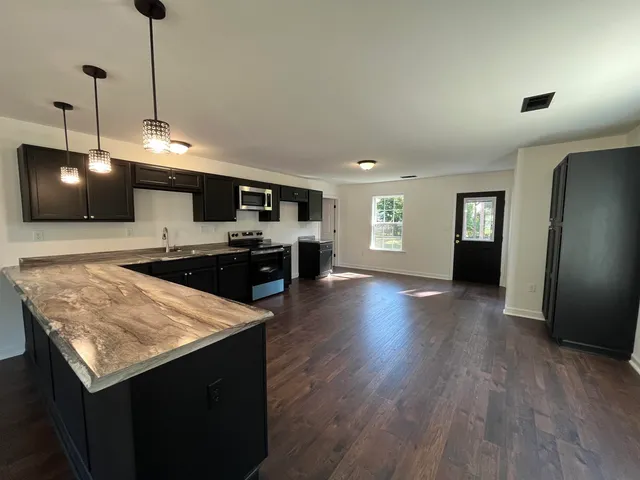 a large kitchen with stainless steel appliances granite countertop a sink a stove top oven a counter space and cabinets