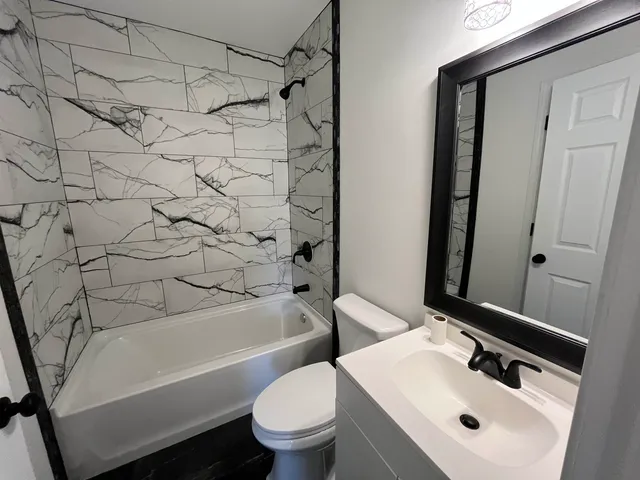 an empty room with wooden floor and kitchen