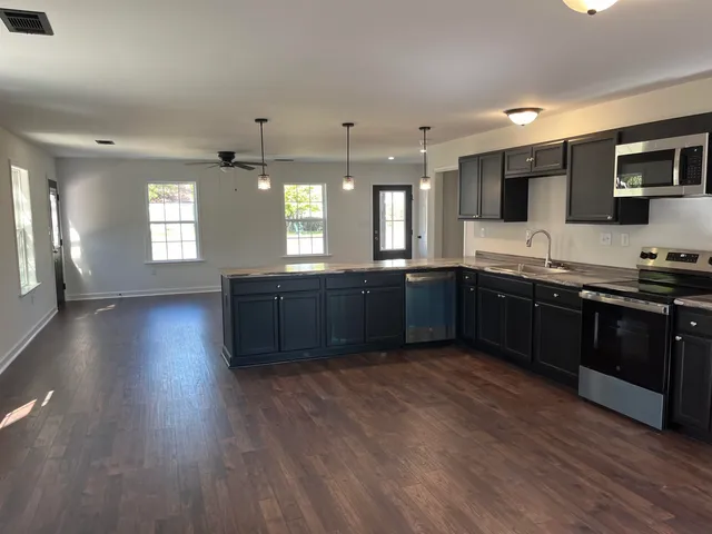 a large kitchen with wooden floors and stainless steel appliances