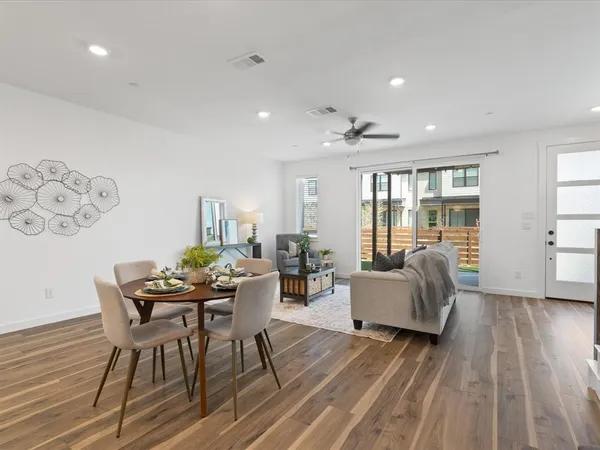 a kitchen with stainless steel appliances kitchen island granite countertop a dining table chairs and a refrigerator
