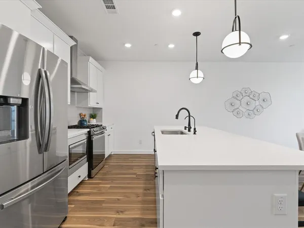 a kitchen with stainless steel appliances granite countertop a stove a refrigerator and a white cabinets