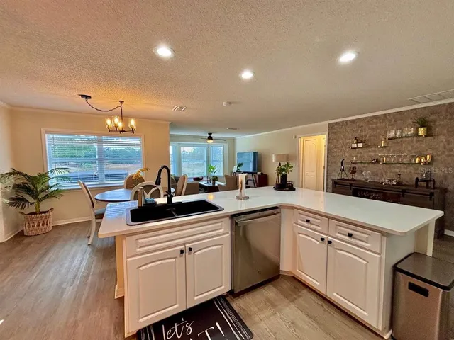 a kitchen with a sink dishwasher stove and white cabinets with wooden floor