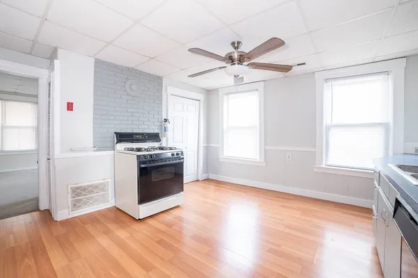 a kitchen with granite countertop a refrigerator a stove a sink and white cabinets