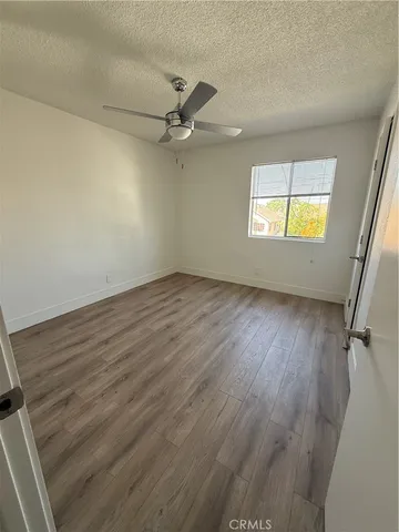 an empty room with wooden floor fan and windows
