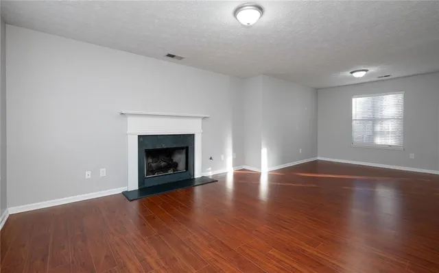 an empty room with wooden floor fireplace and windows