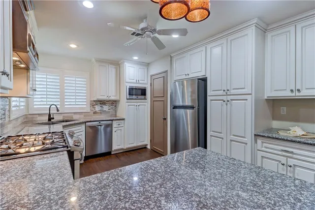 a kitchen with stainless steel appliances granite countertop a sink a stove and cabinets