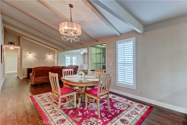 a dining room with wooden floor a chandelier a wooden table and chairs