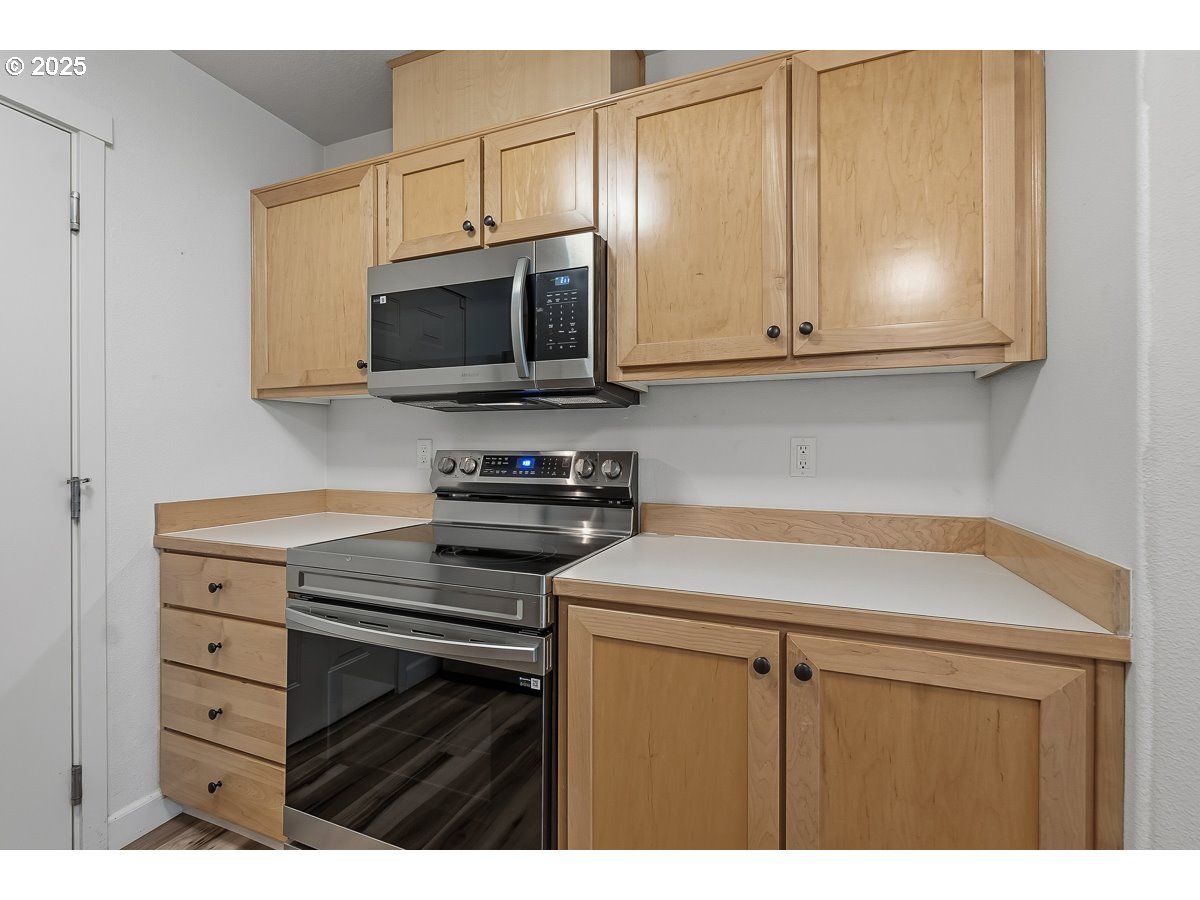 14575 Southwest Magpie Lane, Unit 102 Beaverton, OR 97007 - Photo 8 of 30 a kitchen with stainless steel appliances a stove microwave and sink