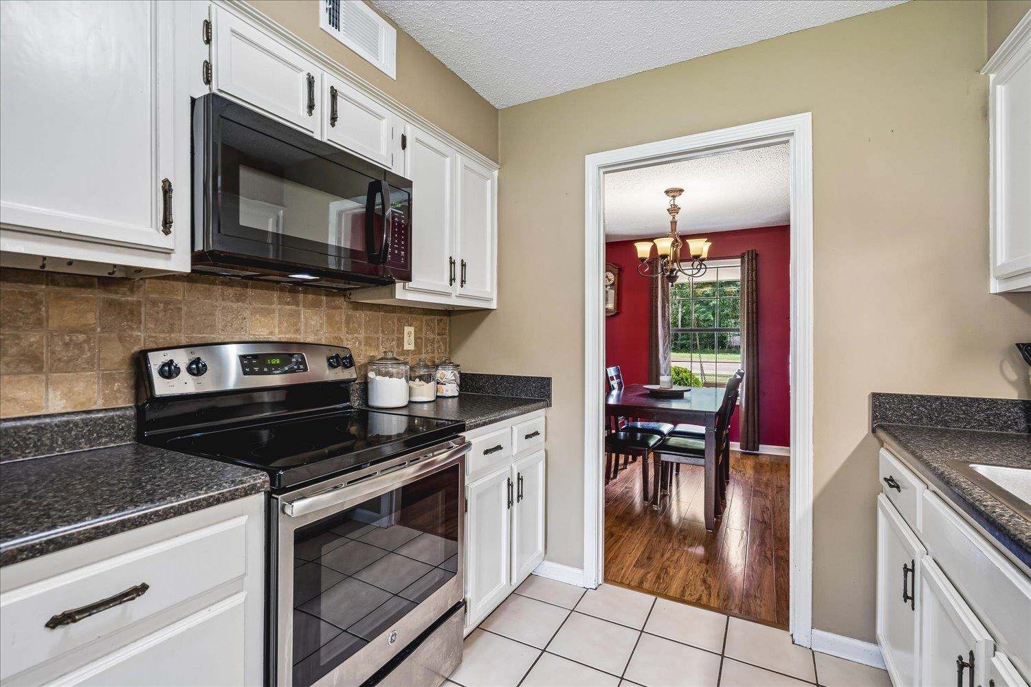 5711 Yale Road Bartlett, TN 38134 - Photo 5 of 29 Kitchen featuring white cabinetry, dark speckled countertops, and a stainless steel electric range with an over-the-range microwave