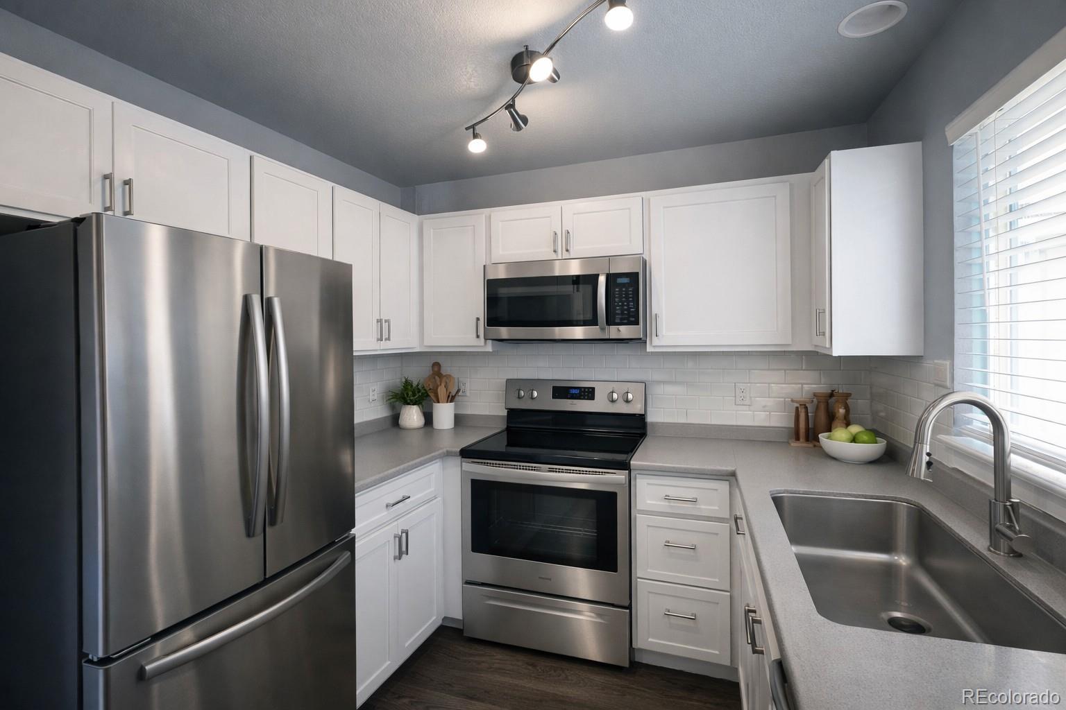 805 Summer Drive Highlands Ranch, CO 80126 - Photo 3 of 10 a kitchen with refrigerator a microwave a sink and white cabinets