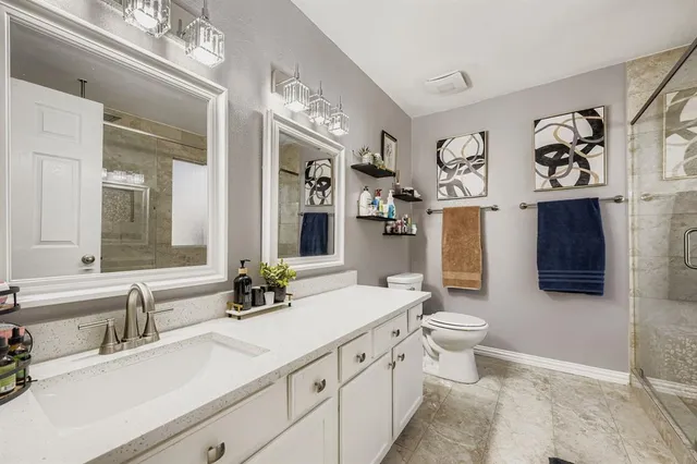 a bathroom with double vanity sink a toilet and a mirror